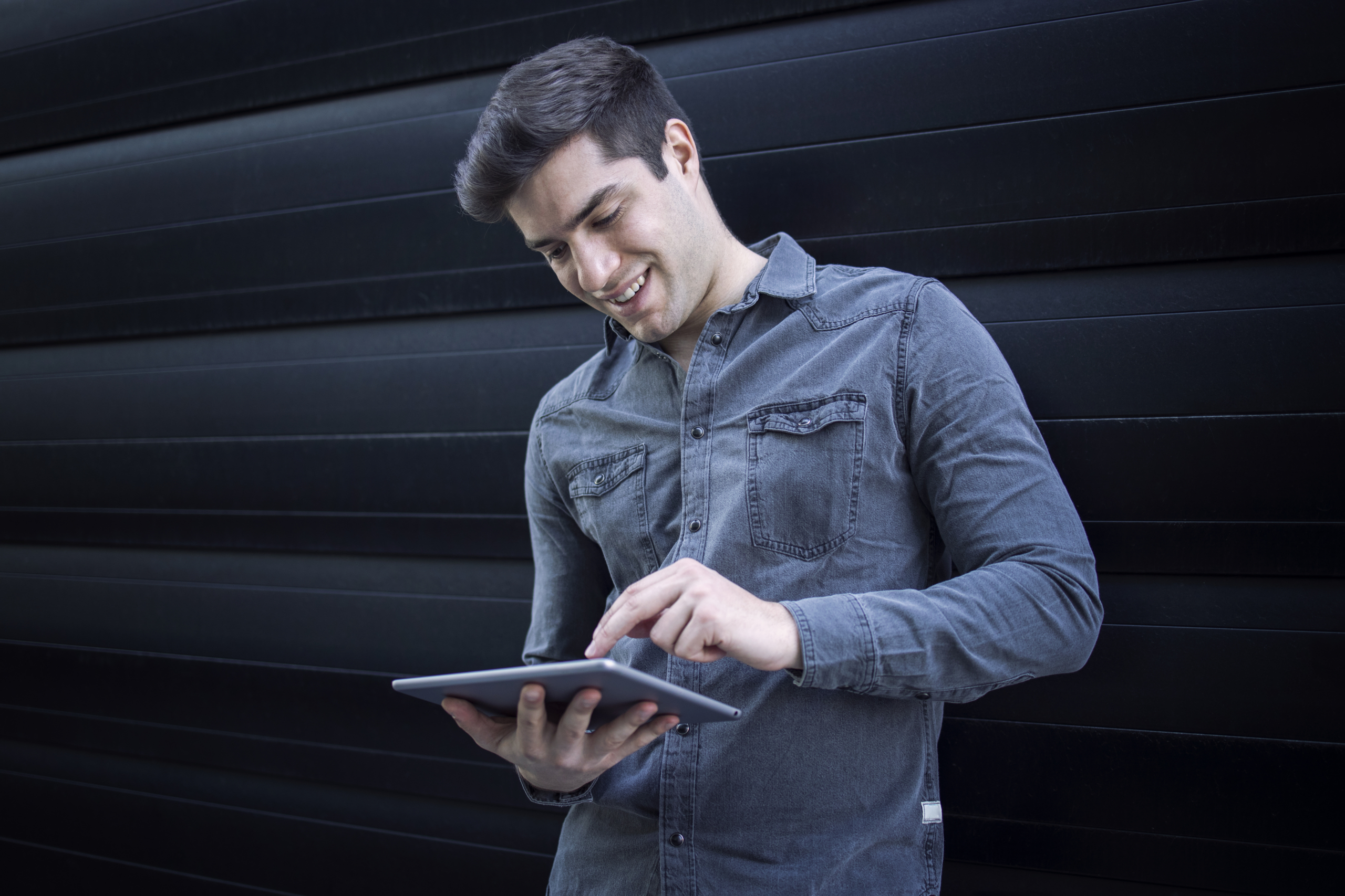Young handsome caucasian man typing on his tablet computer.